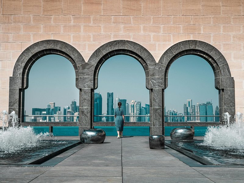 Stone arches on the Doha waterfront framing the West Bay towers across the bay