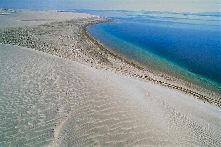 Sand dunes running down to shallow water on the Qatari coast