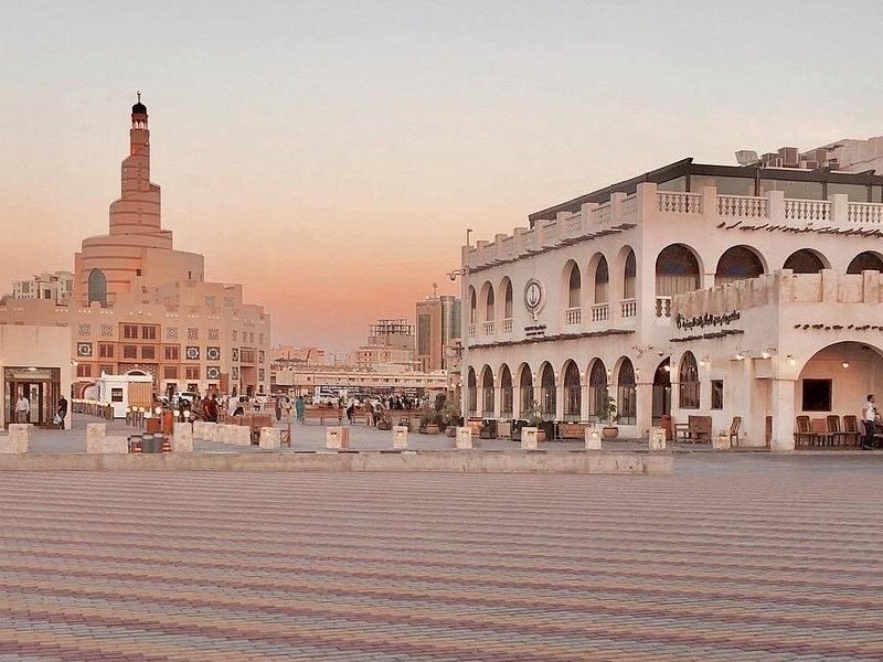 Souq Waqif in Doha at dusk with the spiral minaret of the Fanar centre behind