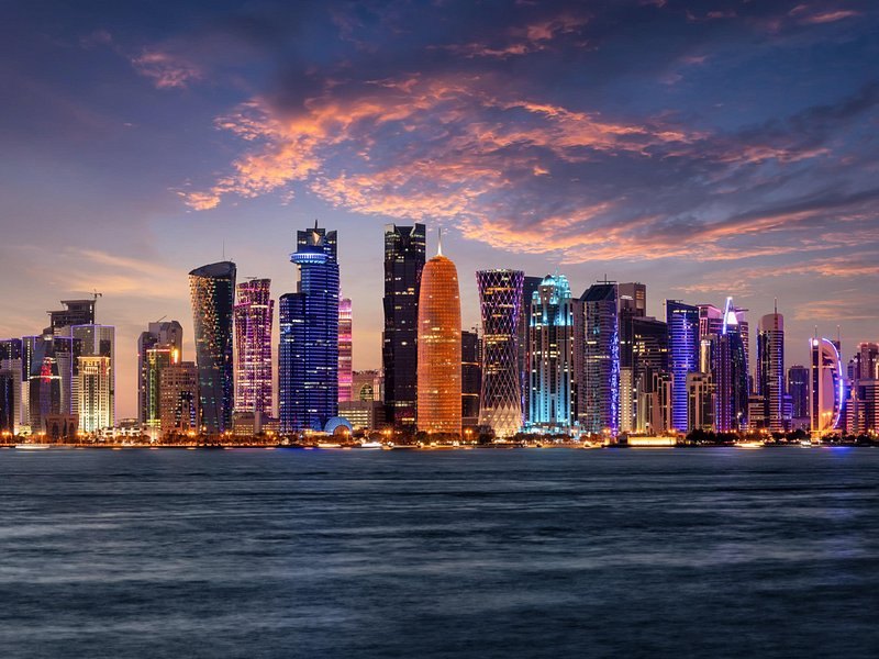 The Doha skyline at dusk with the towers of West Bay reflected in the bay